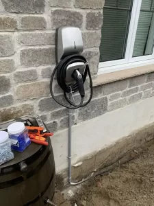 Borne de recharge pour véhicules électriques montée sur un mur en pierre